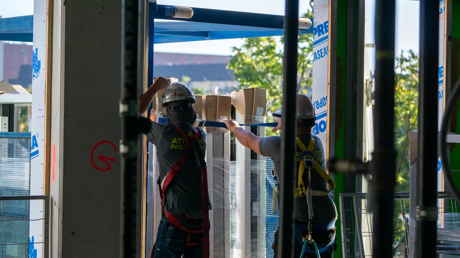 Installateurs travaillant sur une ouverture vitrée dans une maison en construction.