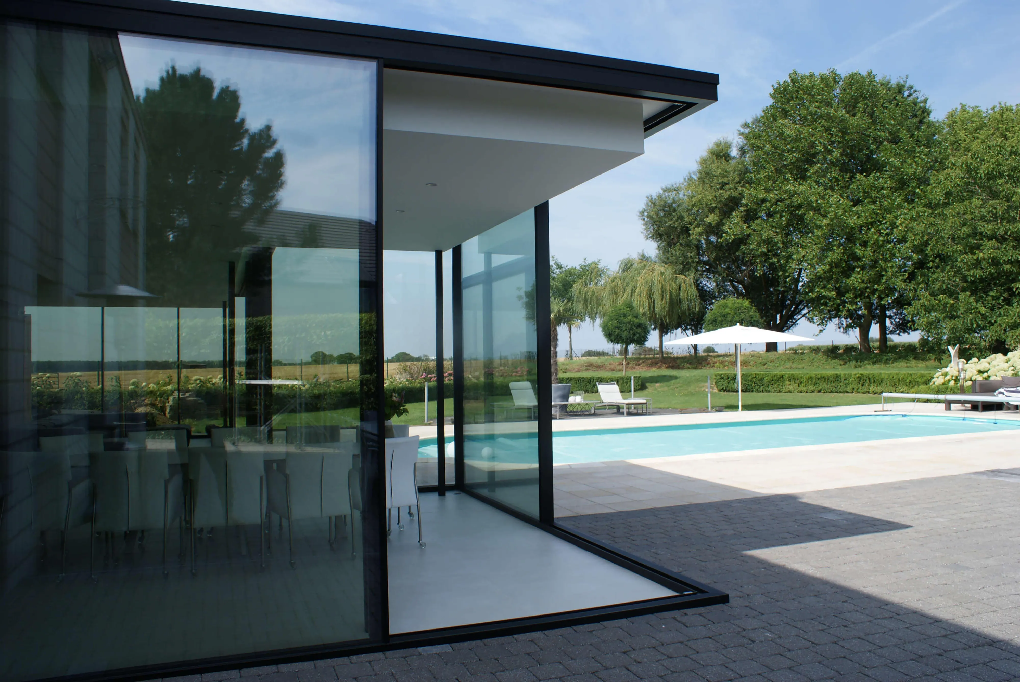 Façade vitrée et portes donnant sur la terrasse d’un bâtiment contemporain.