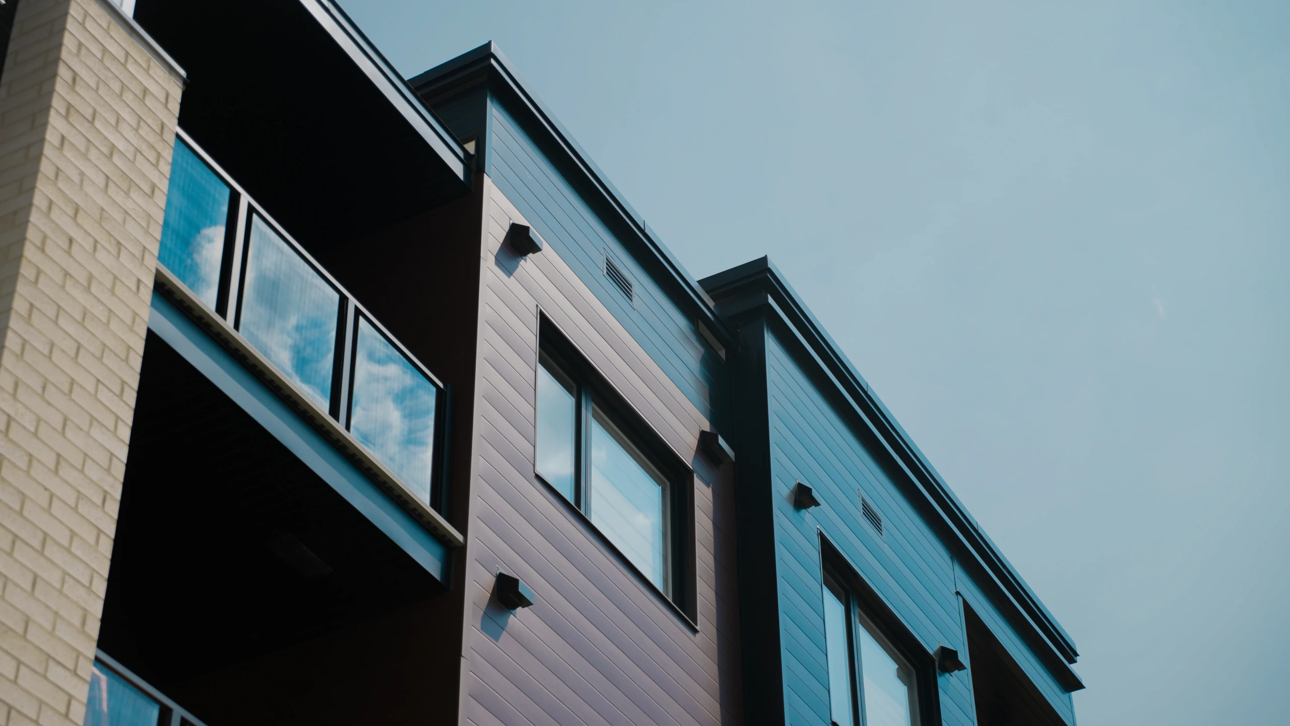 Façade d’un immeuble résidentiel avec fenêtres et balcons vitrés.