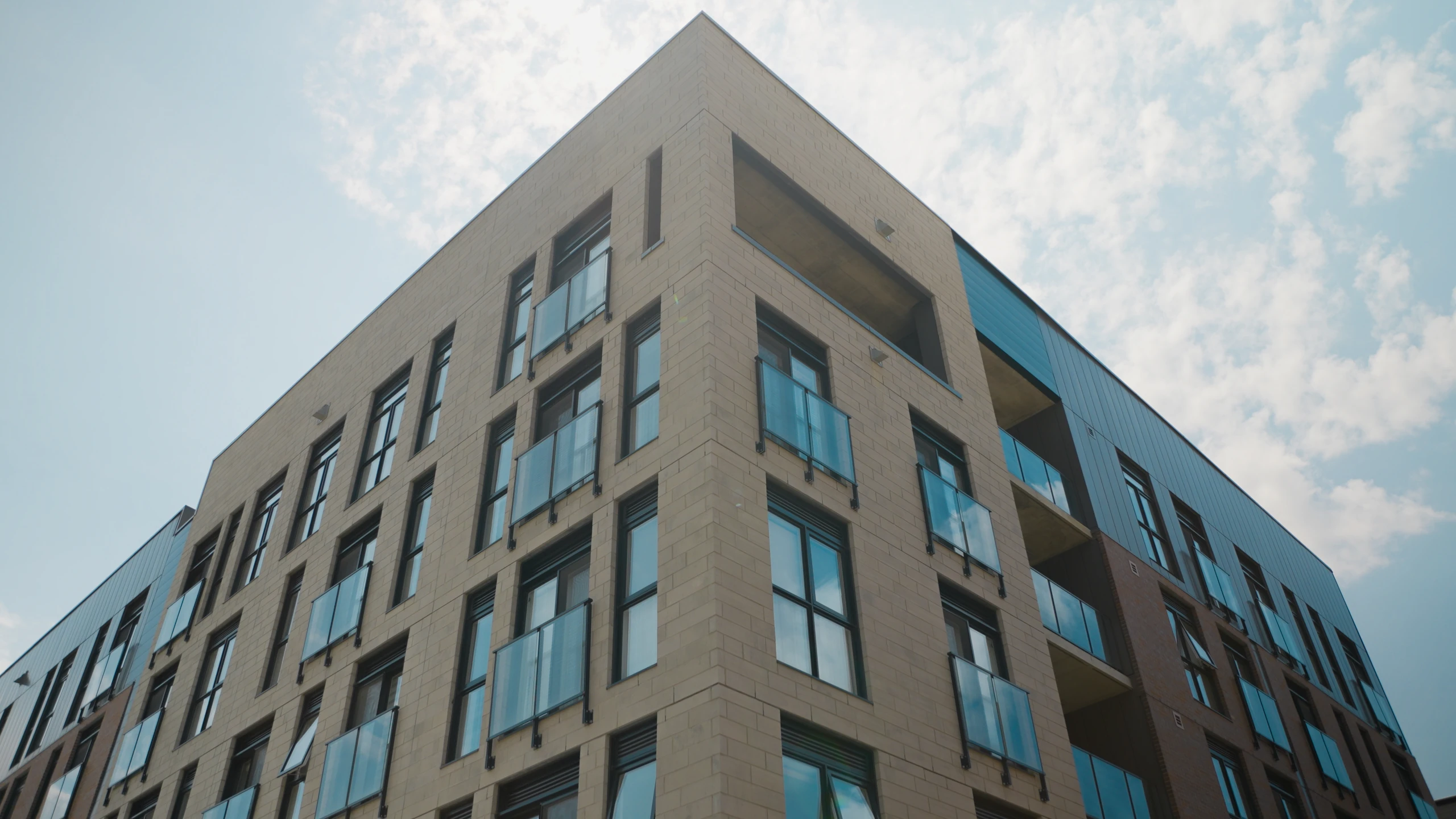Façade d’un immeuble aux fenêtres alignées sous un ciel nuageux.