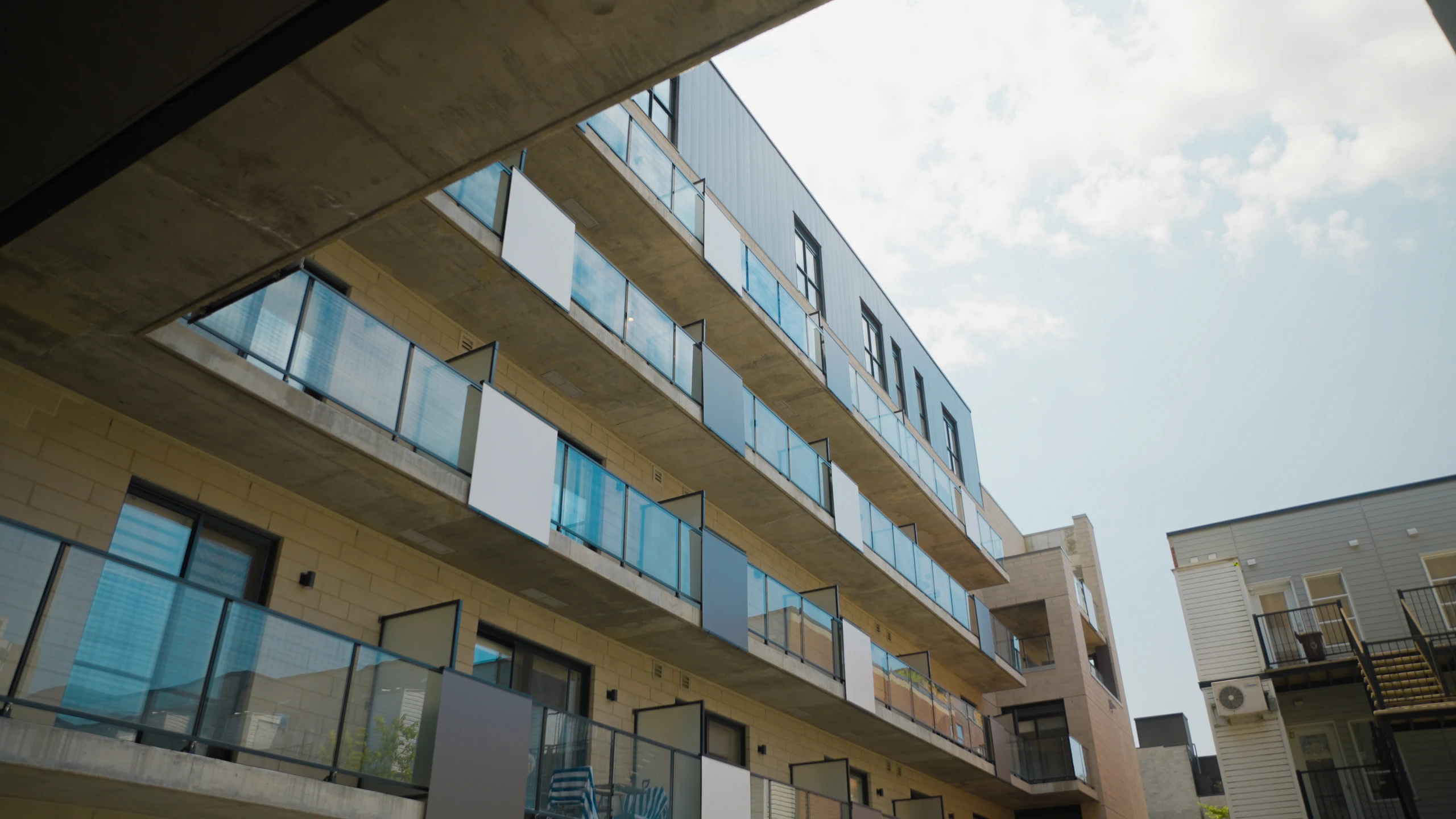 Façade d’un immeuble aux fenêtres alignées sous un ciel nuageux.