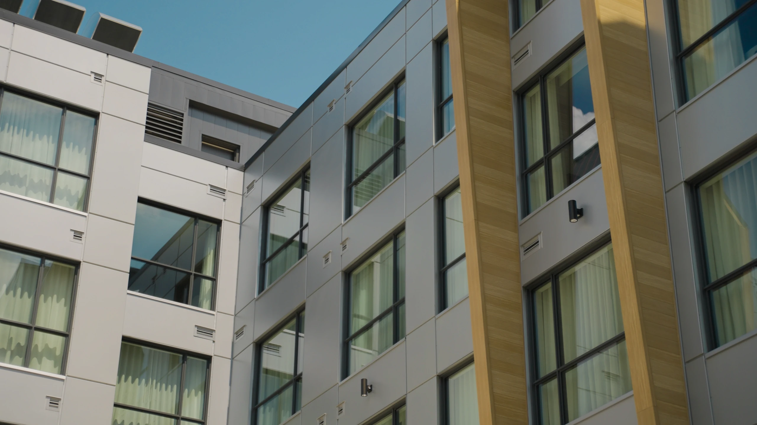 Façade d’un immeuble aux fenêtres alignées sous un ciel nuageux.